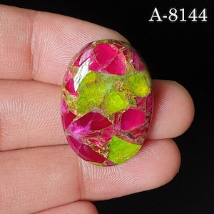 May include: An oval-shaped gemstone featuring a vibrant mosaic pattern of bright magenta and lime green segments separated by metallic gold-colored veins. The stone has a smooth, polished surface and is labeled with the text A-8144 in the corner.