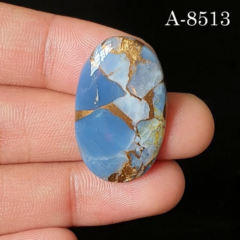 May include: An oval-shaped blue gemstone with a smooth, polished surface featuring intricate, branching copper-colored veins throughout the stone. The text A-8513 is clearly visible in the upper right corner of the image against a dark background.