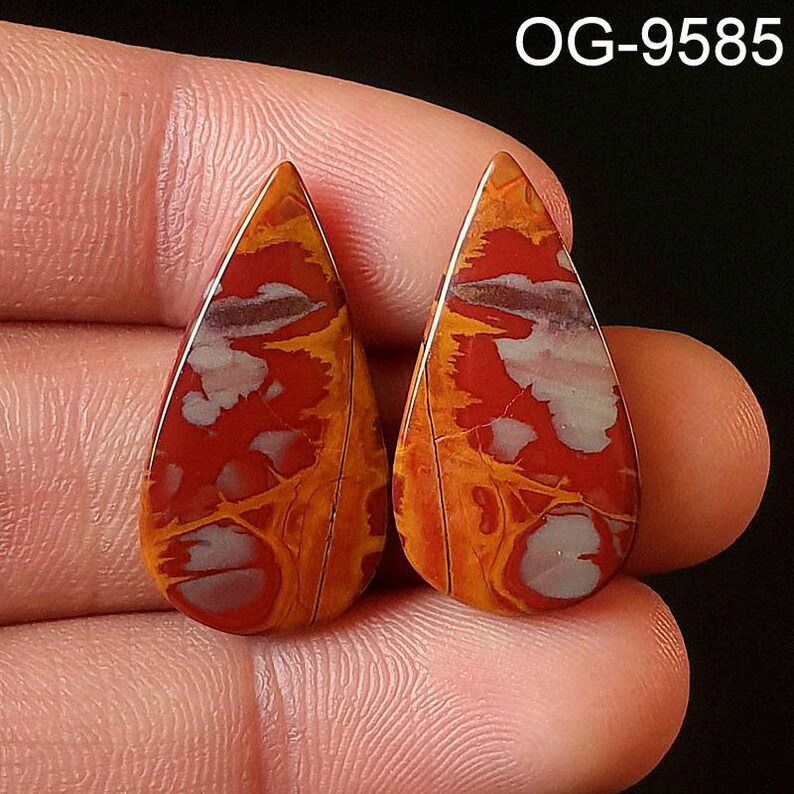 May include: A pair of teardrop-shaped red, orange, and white agate cabochons. The stones have a swirling, marbled pattern.
