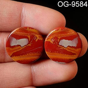 May include: Two round, red, orange, and white agate cabochons with a swirling pattern. The cabochons are approximately 1 inch in diameter.