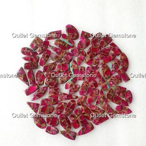 May include: A collection of polished gemstones in various shapes, including ovals, rectangles, and triangles. The stones feature a vibrant red hue with brown and gold veining, and some have turquoise accents. The text "Outlet Gemstone" is visible.
