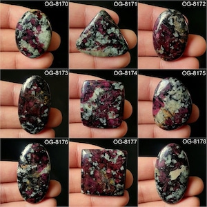 Könnte beinhalten: Neun verschiedene Cabochon-Edelsteine mit einem schwarzen, weißen und rosafarbenen Muster. Die Steine sind alle in verschiedenen Formen und Größen.