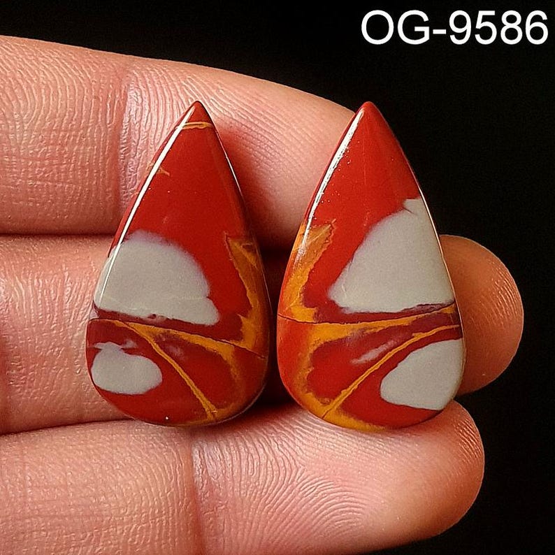 May include: Two teardrop-shaped red, white, and yellow jasper cabochons. The cabochons have a swirling pattern of red, white, and yellow.