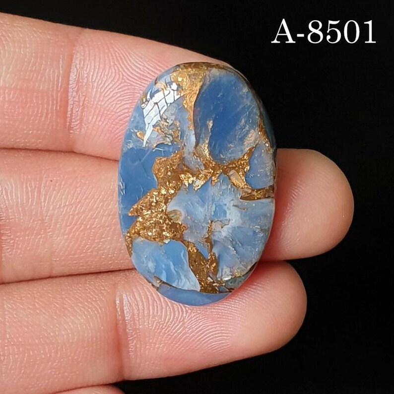 May include: An oval-shaped blue gemstone cabochon featuring intricate, branching metallic copper-colored veins throughout the surface. The stone displays a polished finish with a smooth, rounded top. The text A-8501 is visible in the upper right corner.