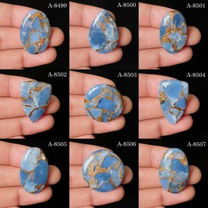 May include: A collection of nine blue and copper-colored cabochons, each featuring a unique cracked pattern. The stones are labeled A-8499 through A-8507 and display various shapes including oval, teardrop, triangular, and circular forms.