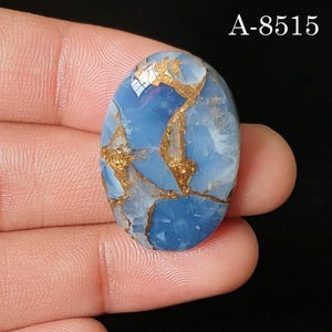 May include: An oval-shaped blue gemstone with a polished surface featuring intricate copper-colored veining throughout the stone. The text A-8515 is clearly visible in the upper right corner of the image against a dark background.