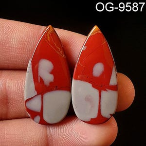 May include: Two teardrop-shaped cabochons of red, white, and brown jasper. The stones have a swirling pattern and are approximately 1 inch in length.