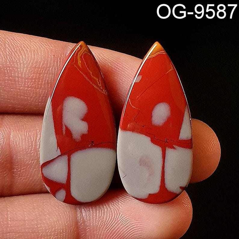 May include: Two teardrop-shaped cabochons of red, white, and brown jasper. The stones have a swirling pattern and are approximately 1 inch in length.
