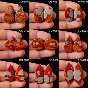 May include: Nine pairs of red, white, and brown agate cabochons in various shapes, including oval, teardrop, and diamond. Each pair is labeled with a unique code, such as OG-9580, OG-9581, and OG-9582.