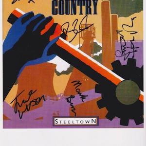 May include: Album cover for Big Country's 'Steeltown'. The artwork features a stylized illustration of a hand holding a gear, with industrial elements in the background. The cover is signed by the band members.