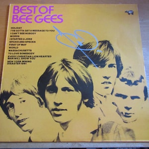 May include: A yellow vinyl record cover with a black and white photo of the Bee Gees band members. The album title "Best of Bee Gees" is printed in pink and black letters. The album tracklist includes "Holiday", "I've Gotta Get a Message to You", "I Can't See Nobody", "Words", "I Started a Joke", "Spicks and Specks", "First of May", "World", "Massachusetts", "To Love Somebody", "Every Christian Lion Hearted Man Will Show You", "New York Mining Disaster 1941".