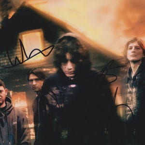 Może przedstawiać: Zdjęcie zespołu pozującego przed płonącym budynkiem. Członkowie zespołu mają na sobie ciemne ubrania. Obraz ma podpisy. Tło jest ognistopomarańczowe i żółte.