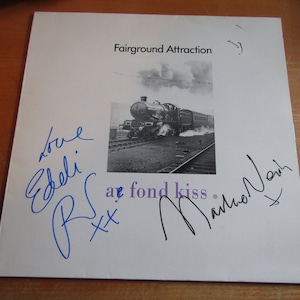 May include: A white record album cover with the text "Fairground Attraction" printed in black. The album cover features a black and white photograph of a steam train on a track. The album is signed by the band members, "Love Edie, R.S. xx a fond kiss,  Mamie Noir".