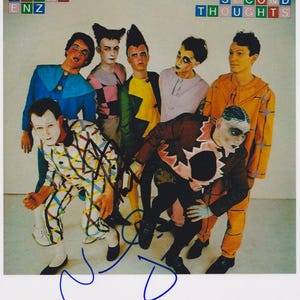 Könnte beinhalten: Vintage-Foto mit einer Gruppe von sieben Personen in Theaterkostümen und -schminke. Das Bild enthält die Texte "SPLIT ENZ" und "SECOND THOUGHTS". Die Gruppe posiert, wobei einige Mitglieder direkt in die Kamera schauen.