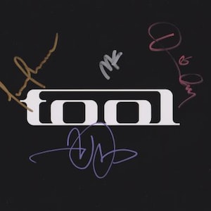 Op de afbeelding: Zwarte achtergrond met het witte woord "TOOL" in een vet, schreefloos lettertype. De afbeelding is gesigneerd met gouden, zilveren, roze en paarse inkt. De handtekeningen zijn in handschrift, wat een persoonlijk tintje aan het ontwerp geeft.