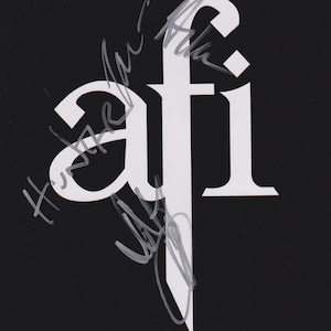 May include: A black background with the white letters "afi" in a stylized font. The letters are partially covered with silver signatures.
