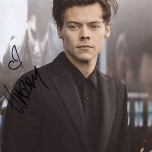 May include: A man with brown hair wearing a black suit jacket and a black button-down shirt. The man is looking at the camera and has a slight smile on his face. The image is signed "Harry".