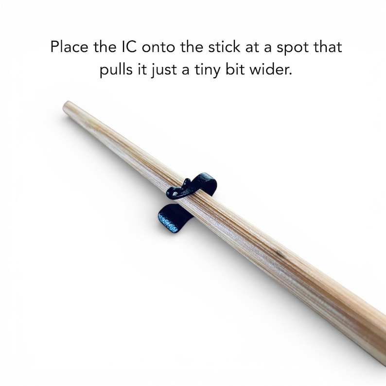 May include: A close-up of a wooden stick with a black, curved clip attached. The text in the image reads, "Place the IC onto the stick at a spot that pulls it just a tiny bit wider."
