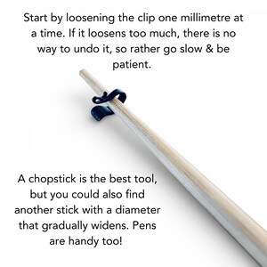 May include: A light-colored chopstick is held by a black clip. Text on the image advises to loosen the clip slowly. Additional text suggests using a chopstick or similar tool. The background is white.