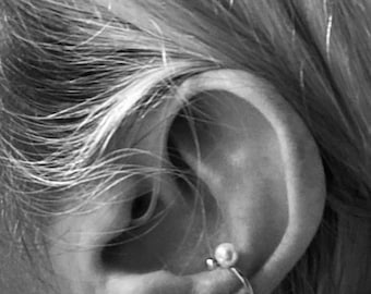 May include: A close-up of a person's ear with a small pearl earring and a silver hoop earring.