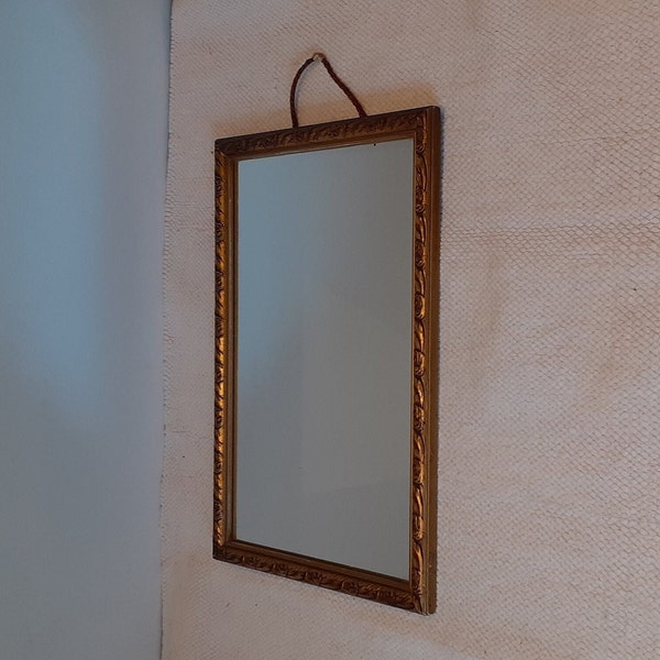 A small hall or bedroom mirror from the 40s, decorated wooden gold-coloured frame, small roses are cut in the frame