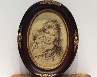 May include: Oval framed artwork featuring a pencil sketch of a mother and child. The frame is dark brown with gold accents at the corners and around the inner edge. The artwork depicts a tender embrace.