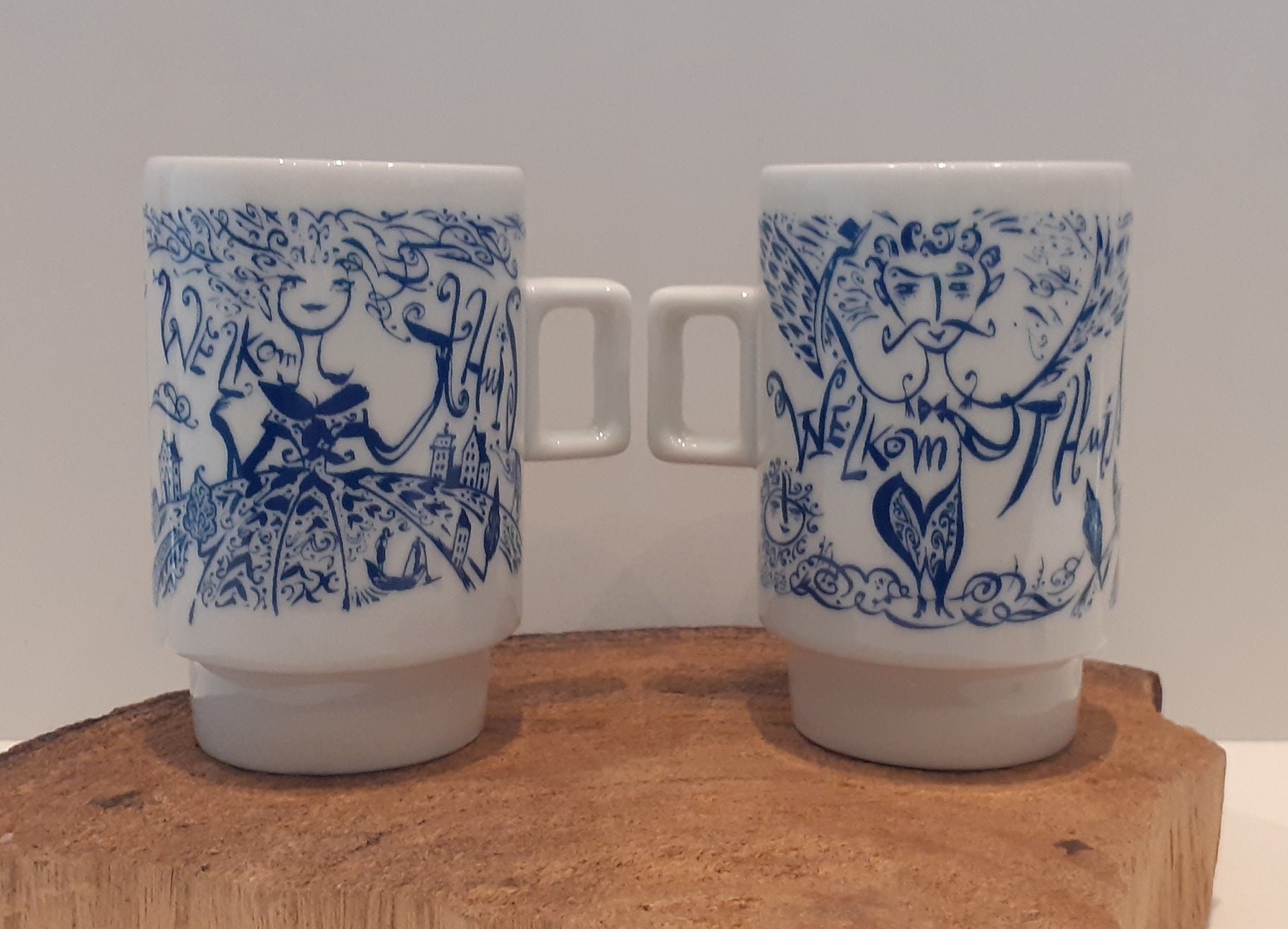 Mosa - Holland, design by Jan des Bouvrie, single cup or set of two white cups, images of two figures. text 'Welcome Home'