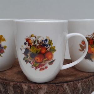A nice set of three beautiful, large white ceramic mugs with a sturdy handle, and images of fruit, content 250 ml, 1970s