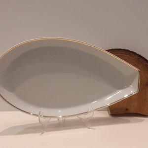 Op de afbeelding: Een witte ovale serveerschaal met een gouden rand. De schaal staat op een houten standaard.