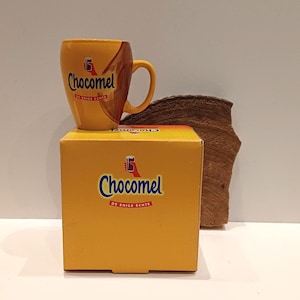 Chocomel, en fin ny mugg! med en bild av en stor droppe, logotypen för den lilla handen med Chocomel, och i originalförpackningen.