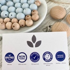 Pode incluir: Close-up de um cart&atilde;o com quatro &iacute;cones: Livre de BPA, N&atilde;o t&oacute;xico, Aprovado pela T.E.A. e Silicone de grau alimentar. Os &iacute;cones est&atilde;o em um c&iacute;rculo branco com texto azul e borda azul. O cart&atilde;o tem um fundo cinza claro com tr&ecirc;s folhas cinza escuras na parte superior central.