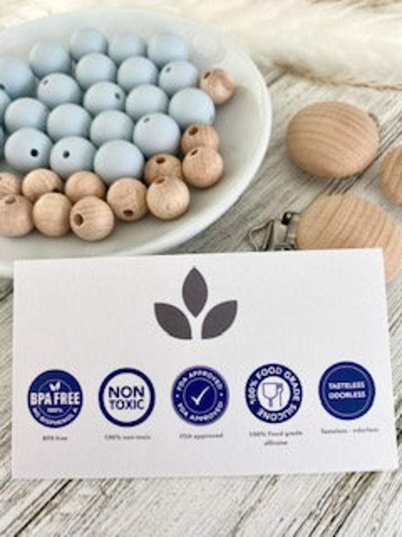 Pode incluir: Close-up de um cart&atilde;o com quatro &iacute;cones: Livre de BPA, N&atilde;o t&oacute;xico, Aprovado pela T.E.A. e Silicone de grau alimentar. Os &iacute;cones est&atilde;o em um c&iacute;rculo branco com texto azul e borda azul. O cart&atilde;o tem um fundo cinza claro com tr&ecirc;s folhas cinza escuras na parte superior central.
