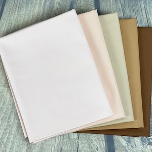 May include: Five fabric swatches in various shades of brown, beige, and pink. The swatches are arranged in a stack, with the lightest colour on top and the darkest colour on the bottom.