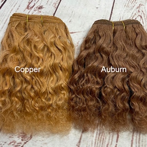 May include: Two bundles of wavy human hair extensions, one in a copper color and the other in an auburn color. The hair is arranged in a side-by-side comparison.