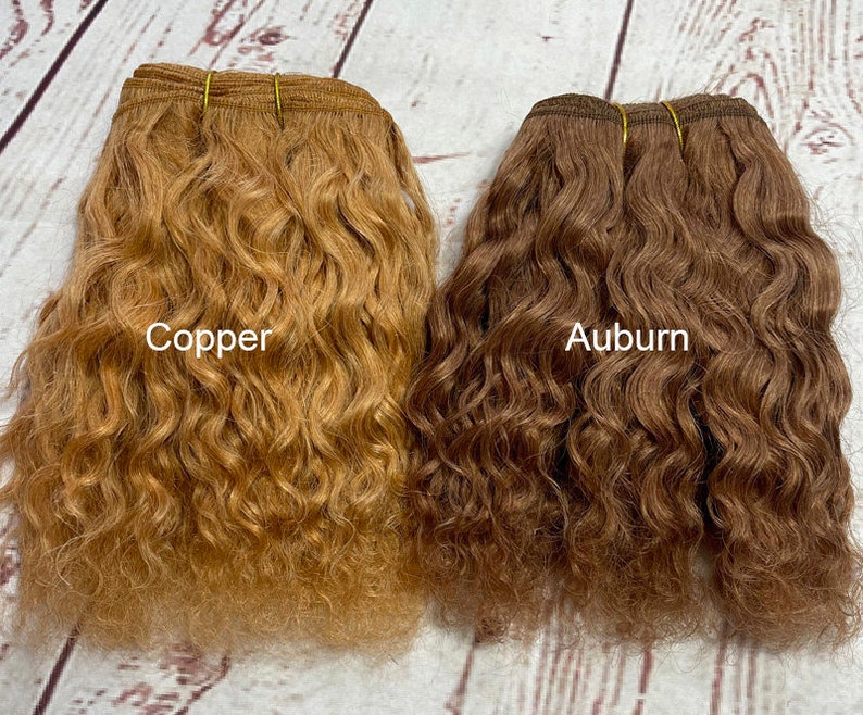 May include: Two bundles of wavy human hair extensions, one in a copper color and the other in an auburn color. The hair is arranged in a side-by-side comparison.
