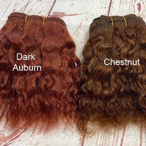 May include: Two bundles of wavy human hair extensions, one in dark auburn and one in chestnut brown.