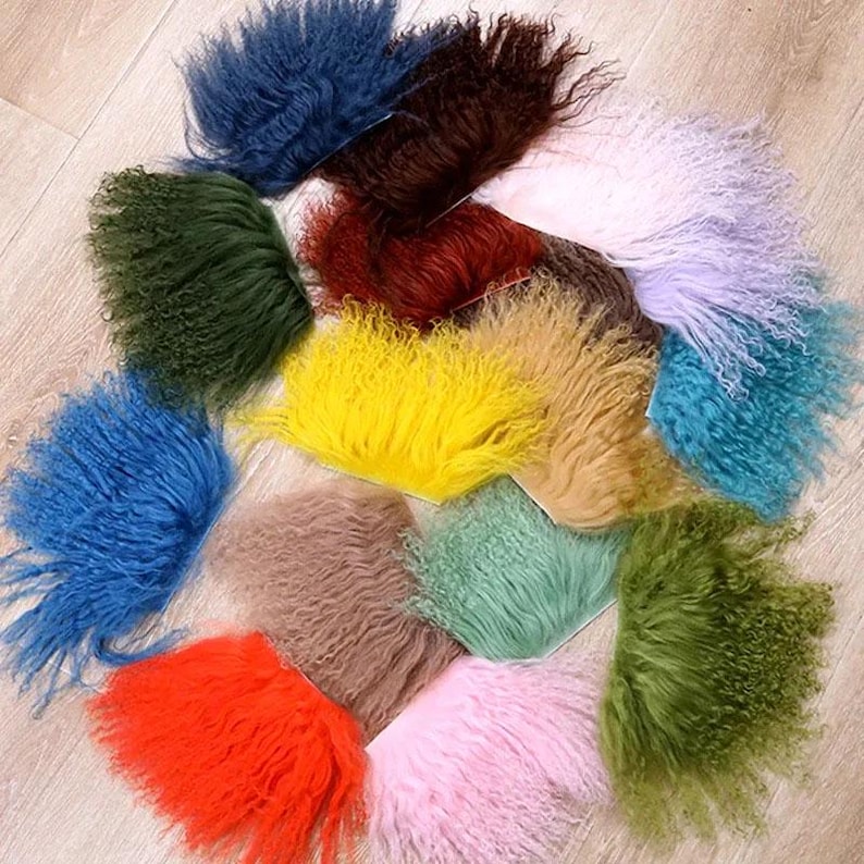 May include: A collection of multiple swatches of curly, long-pile faux fur fabric in a variety of vibrant colors including blue, dark green, yellow, orange, pink, brown, tan, and light green, arranged in a circular pattern on a light surface.