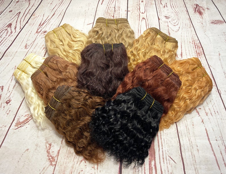 May include: A variety of human hair wefts in different colors and textures, including blonde, brown, red, and black. The wefts are arranged in a circle on a wooden surface.