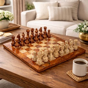 May include: A wooden chess set with dark and light pieces arranged on a checkered board. The board is set on a wooden table, with a white mug and coaster in the foreground. The chess pieces are brown and beige.