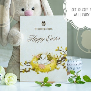 May include: An Easter greeting card with a bunny in a nest, the words "Happy Easter" and "For Someone Special" are written on the card. A plush bunny and a candle are in the background. The card has a floral design.