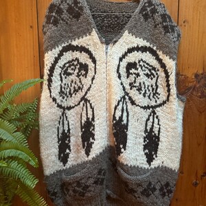 May include: A brown and white knitted vest with a zipper closure and a dreamcatcher design. The vest has two pockets on the bottom.