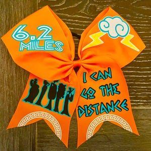 May include: Orange cheer bow with a lightning bolt and cloud design. The bow also features the text "6.2 Miles" and "I Can Go The Distance" with a Greek key design.