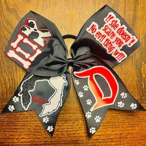 May include: Black and red cheer bow with a white Dalmatian dog, bones, and the text "If she doesn't scare you no evil thing will". The other side of the bow has a red "D" with white paw prints.