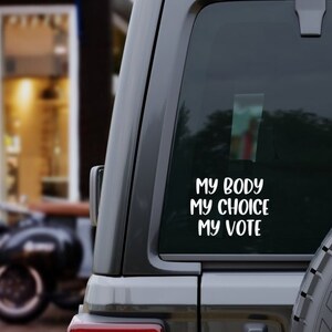 May include: A black car with a white sticker on the back window that says "My Body My Choice My Vote".