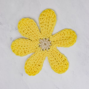May include: A yellow crocheted flower with a smaller beige crocheted flower in the center.