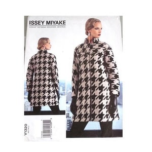 Puede incluir: Un patrón Vogue para un abrigo Issey Miyake. El abrigo es de pata de gallo en blanco y negro con cuello alto y cremallera. El patrón muestra el abrigo en una modelo de frente y de espalda.