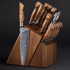 May include: A wooden knife block with a set of 14 knives and a pair of kitchen shears. The knives have wooden handles and a patterned blade. The block is made of dark wood and has a logo on the front.
