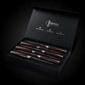 Pu&ograve; includere: Un set di sei coltelli da bistecca con manici in legno in una scatola nera. La scatola &egrave; aperta e i coltelli sono disposti in fila. La scatola ha il logo "SENKEN KNIVES" stampato all'interno.