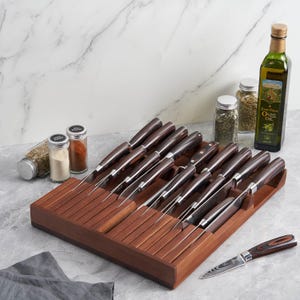 May include: A collection of kitchen knives with brown handles and steel blades, presented in a wooden knife block. The image also shows olive oil, spices, and a single knife.