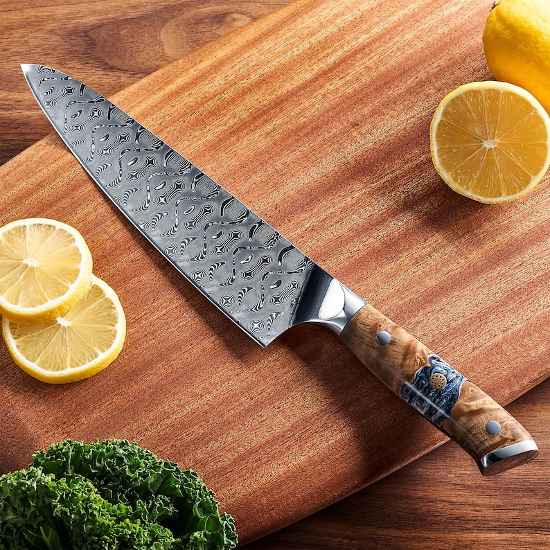 Puede incluir: Un cuchillo de chef de acero inoxidable con una hoja estampada y un mango de madera. El cuchillo est&aacute; sobre una tabla de cortar de madera con rodajas de lim&oacute;n y verduras de hoja verde.